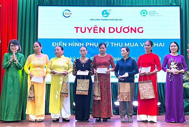 Những người làm nghề ve chai và các ngành nghề khác bận áo dài lên nhận hoa, quà tại TP Hội An vào sáng 7-3 - Ảnh: THÙY ANH
